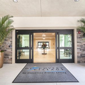 The entrance to a building with glass doors and a welcome mat on the floor.
