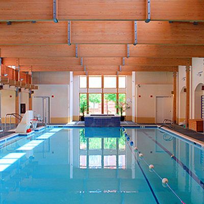 A serene indoor swimming pool with wooden ceiling and natural lighting.