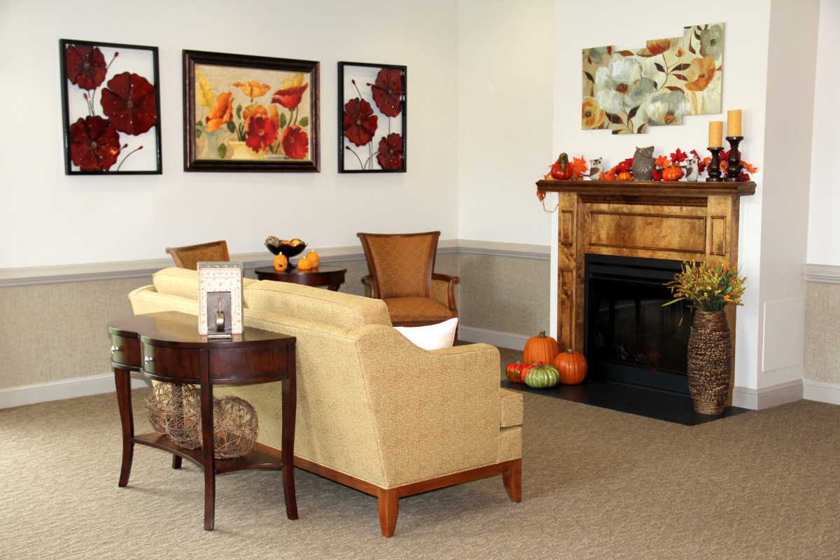 A cozy living room with a sofa, fireplace, and autumn-themed decorations.