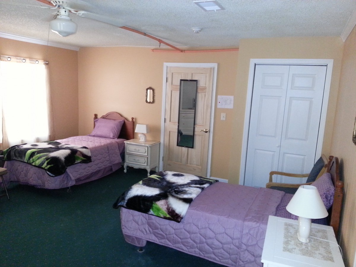 A cozy bedroom with twin beds and pastel-colored walls.