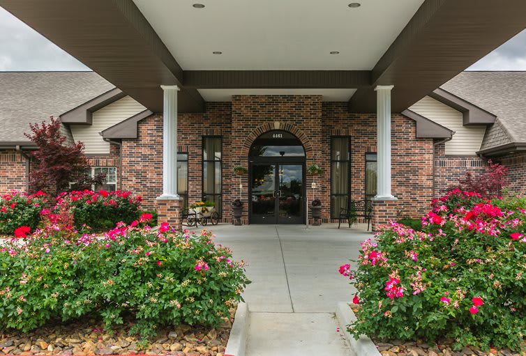 Entrance to a building featuring brick architecture and vibrant flower landscaping.
