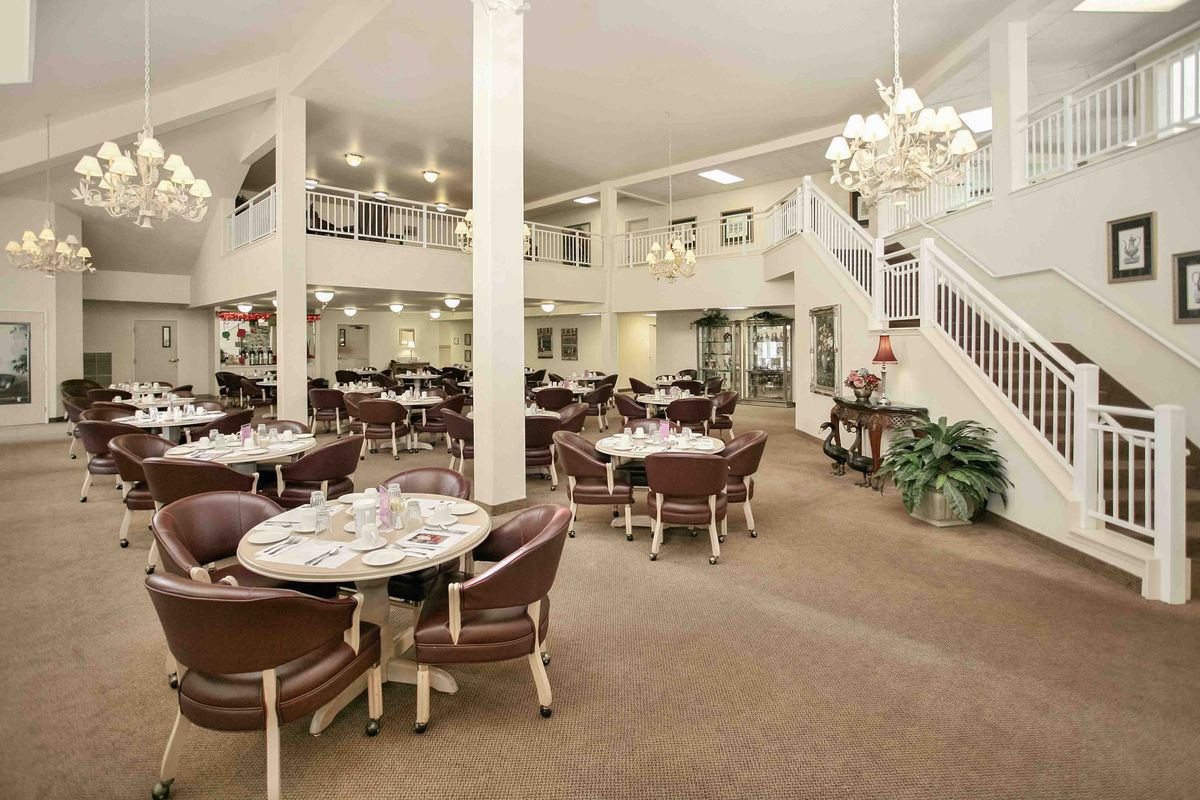 A spacious dining area with tables and chairs, bright lighting, and elegant chandeliers.