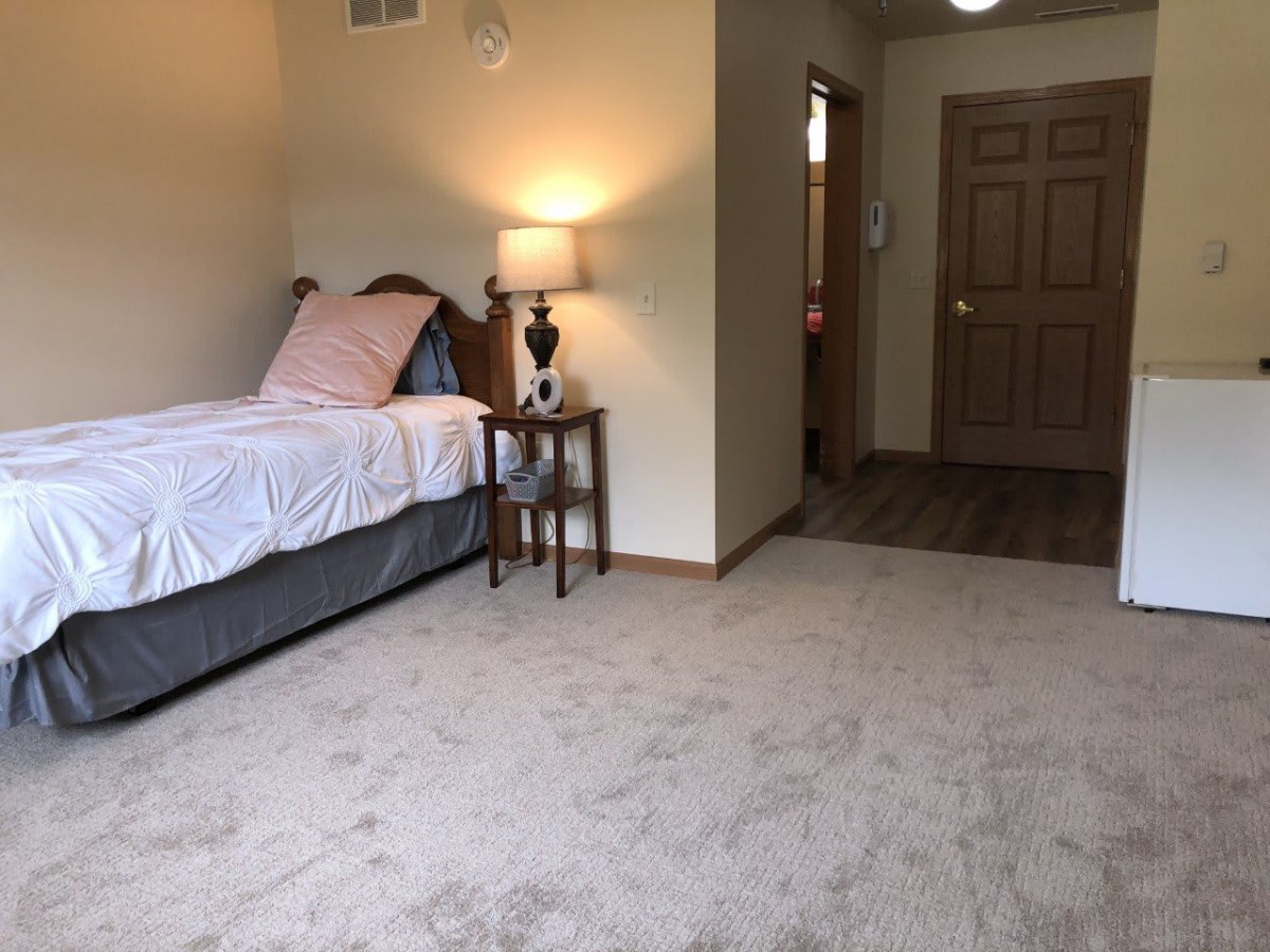 A cozy bedroom with a single bed and lamp on a nightstand.