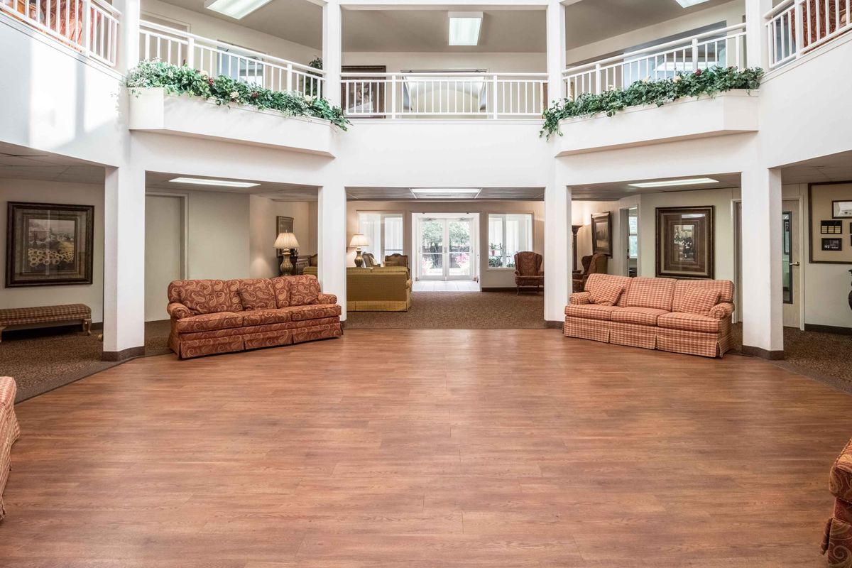 A spacious lobby area with wooden flooring, featuring sofas and decorative lighting.