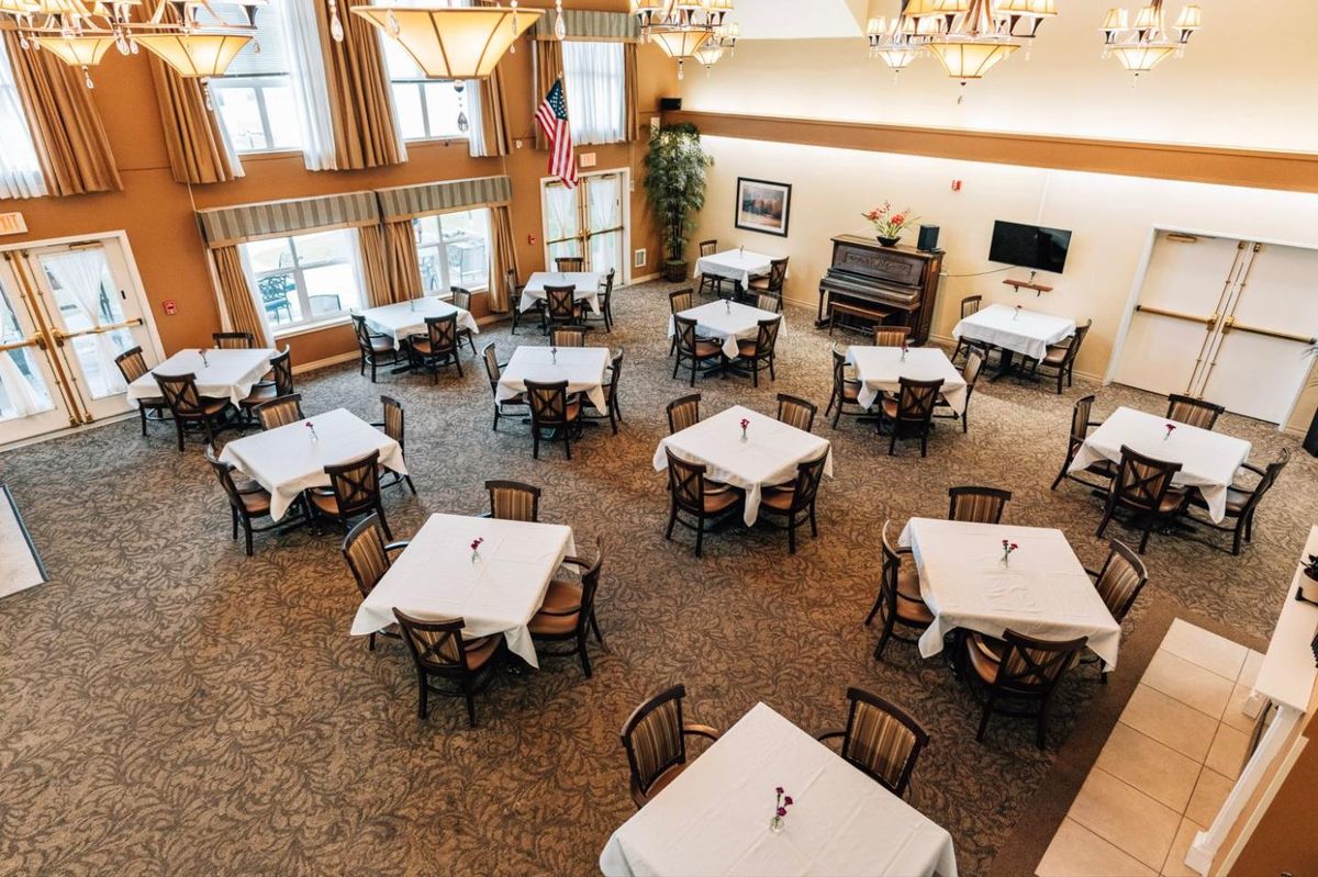 A spacious and elegantly decorated dining room with multiple tables and chairs arranged neatly beneath chandeliers.