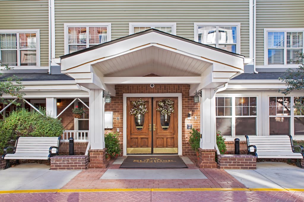 The inviting entrance of a charming building with wooden doors and white columns.