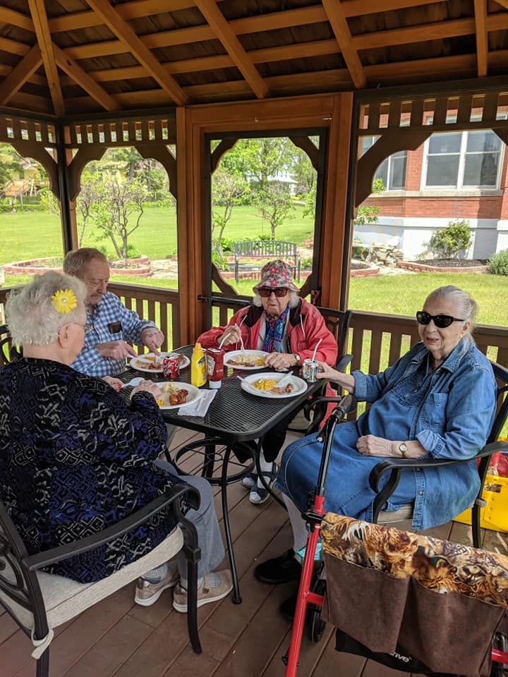 A group of seniors enjoying a meal together in a gazebo.