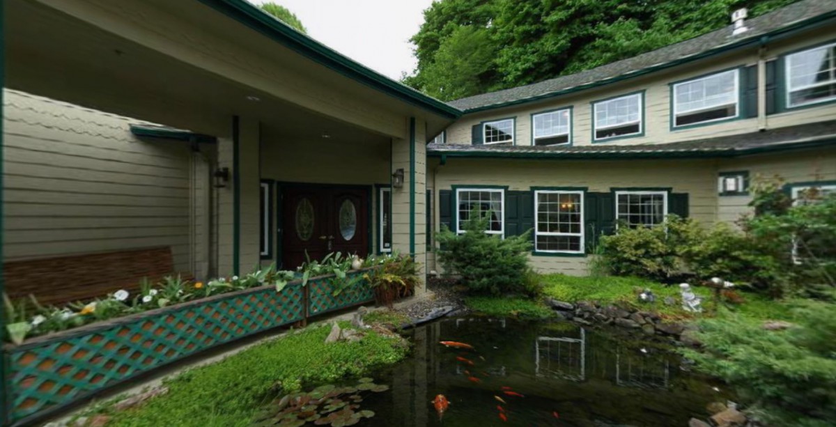 A beautiful house exterior with a pond and lush greenery.