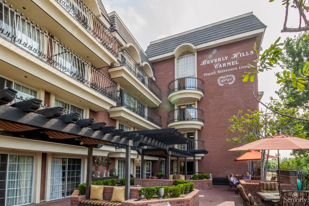A charming hotel with a brick facade features multiple balconies and a cozy courtyard with outdoor seating.