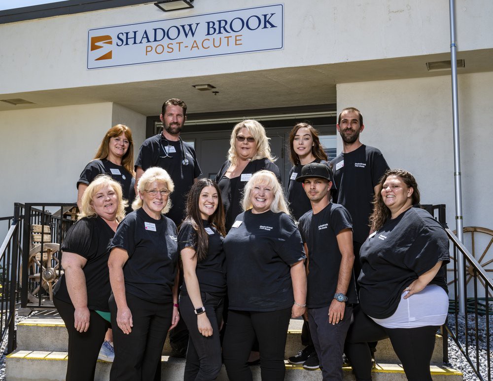 A group photo of a team standing in front of the Shadow Brook sign.
