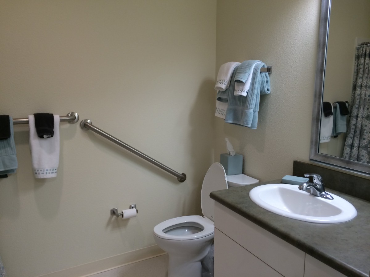 A clean and accessible bathroom with a toilet, sink, and grab bar.