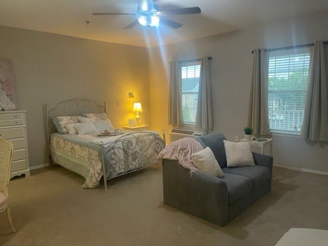 A cozy bedroom with a bed, couch, and soft lighting.