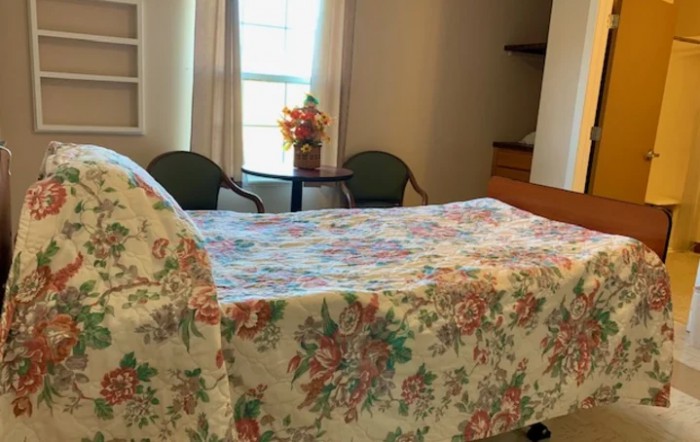 A cozy bedroom with a floral bedspread and a small table by the window.