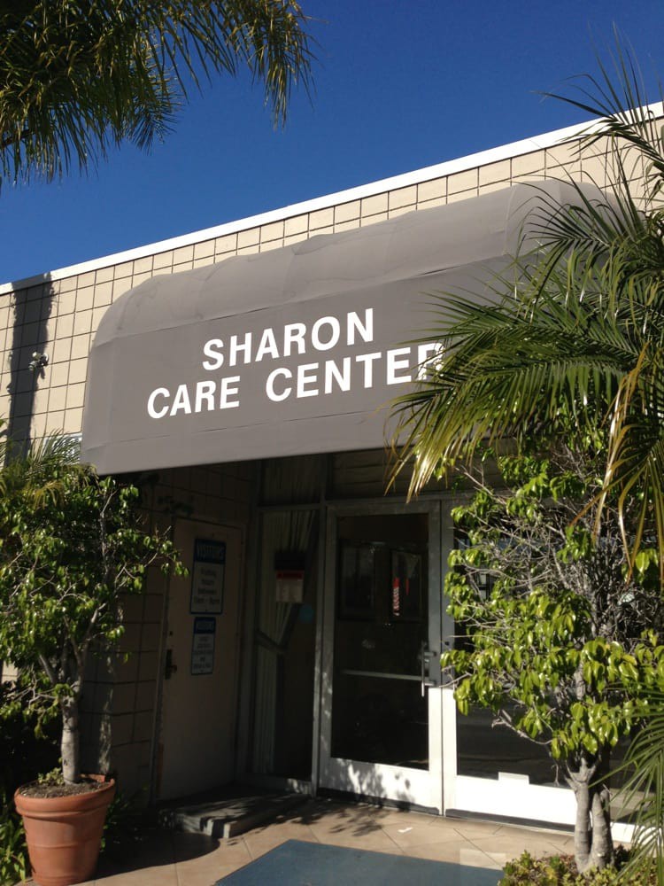 Entrance to the Sharon Care Center with a gray awning and surrounding greenery.