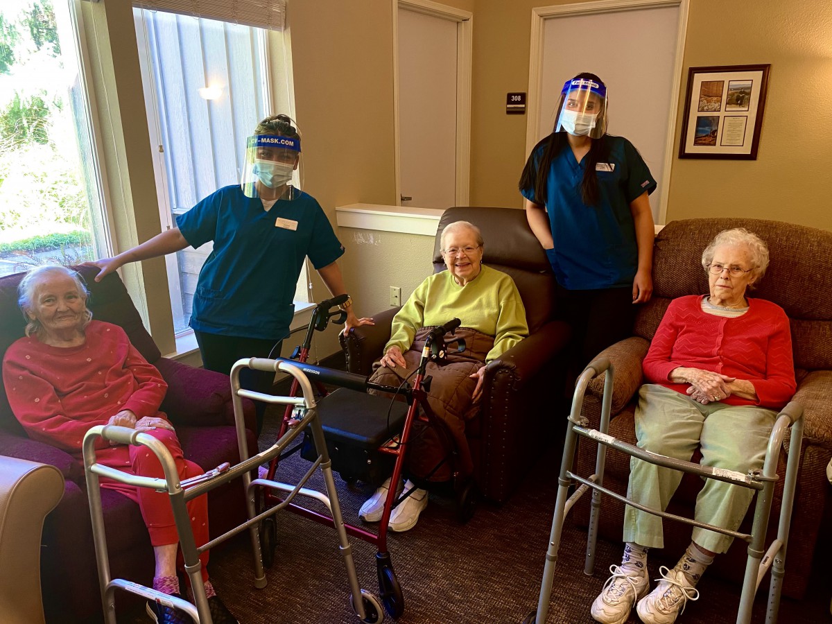 Seniors and caregivers at a nursing home, wearing masks for safety.