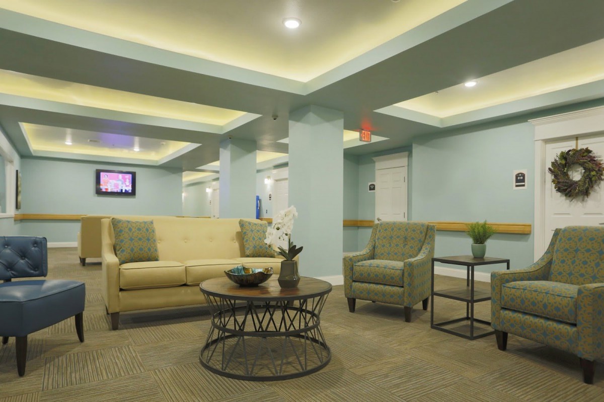 A modern lobby interior featuring comfortable seating with sofas and chairs around a central coffee table under ambient lighting.
