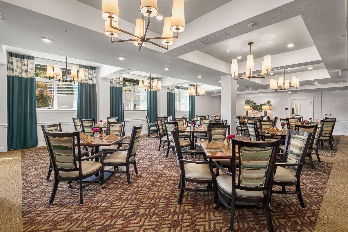 An elegant dining area with neatly arranged tables and chandeliers.