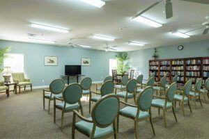 An empty meeting room with arranged chairs facing a television and bookshelf.