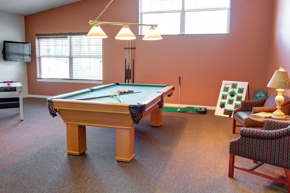 A cozy game room featuring a billiards table with overhead lighting and seating.