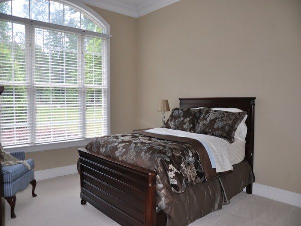 A cozy bedroom with a single bed and a large window providing natural light.