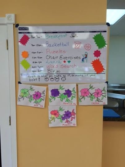 A decorated whiteboard displaying an event announcement with colorful decorations and floral artwork.