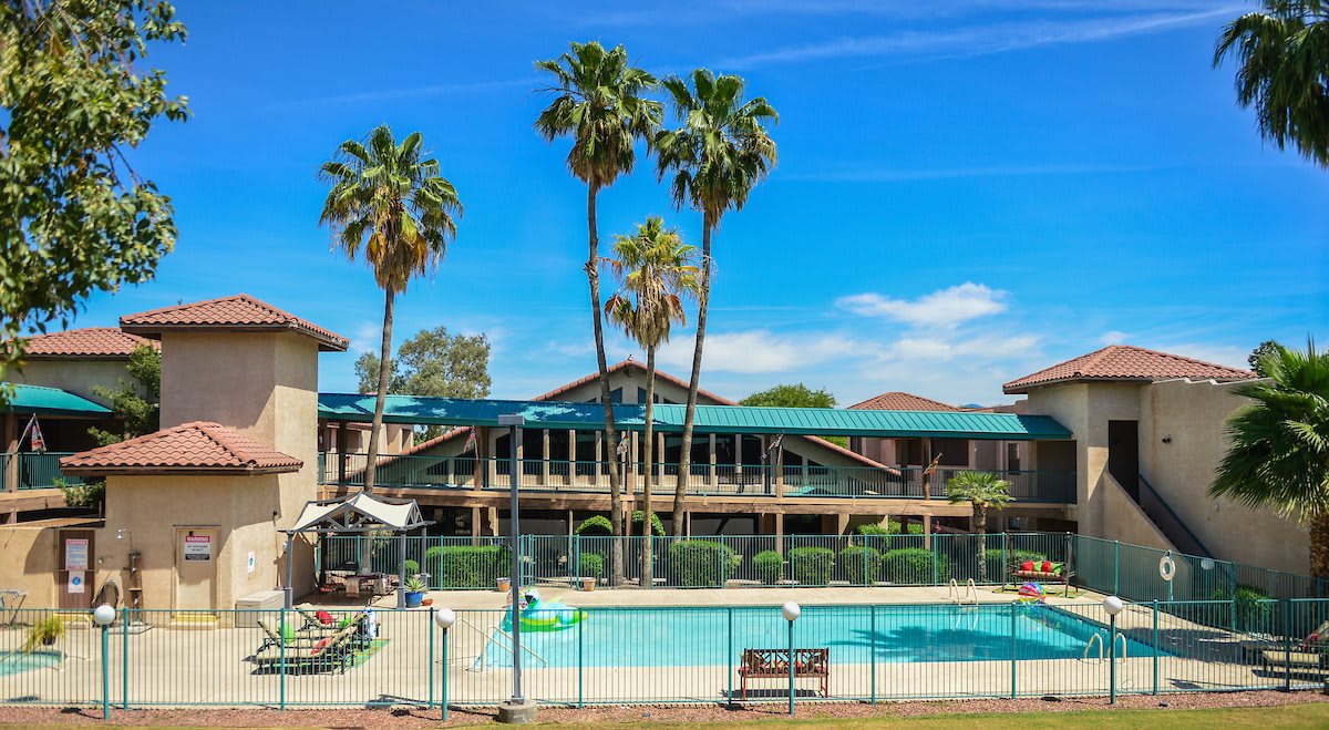 A sunny resort with a pool surrounded by palm trees.