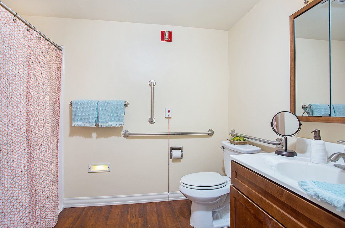 A spacious bathroom with accessibility features including grab bars and a neatly arranged towel rack.