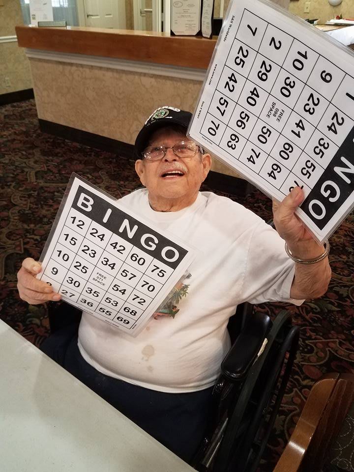 An elderly person happily holding bingo cards.