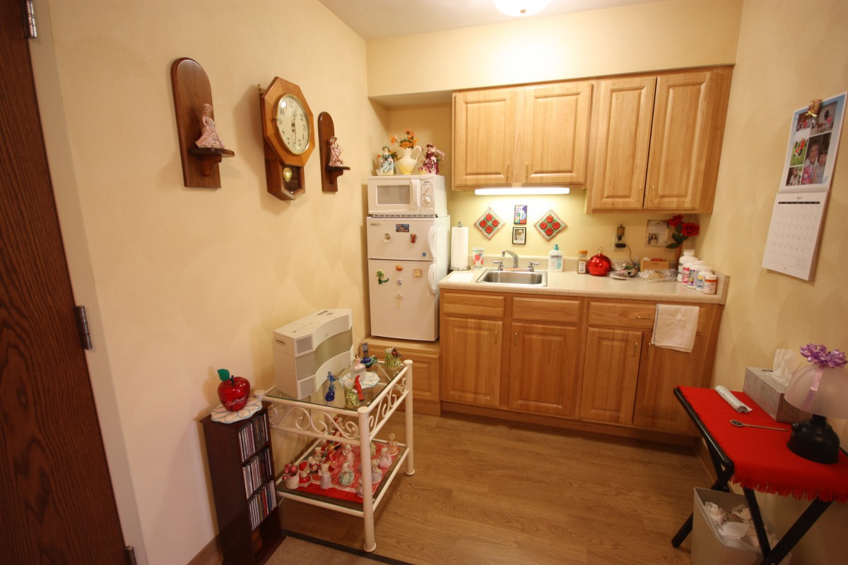 Cozy kitchen with wooden cabinets and a small refrigerator, featuring charming decor elements.
