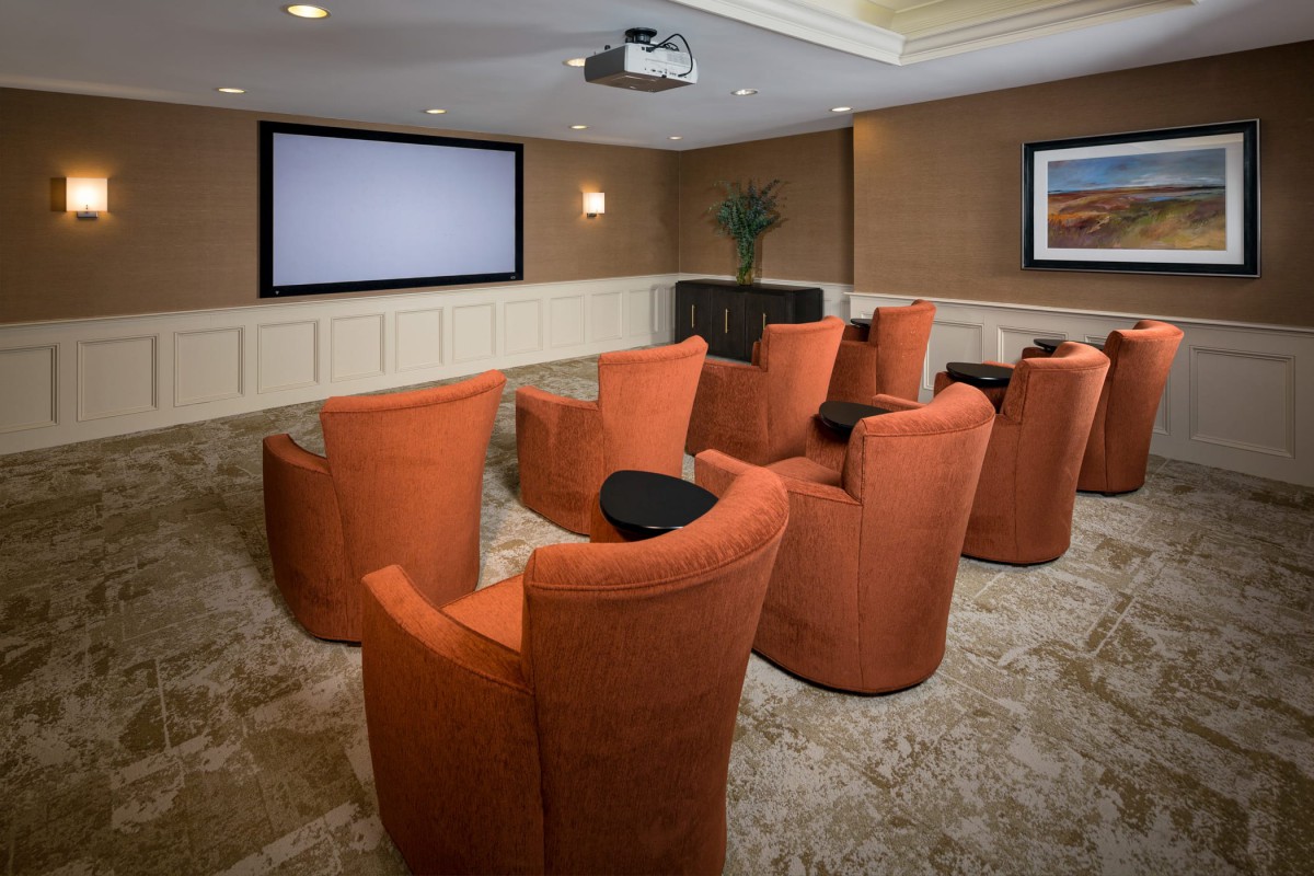 A luxurious home theater equipped with orange seating and a large screen.