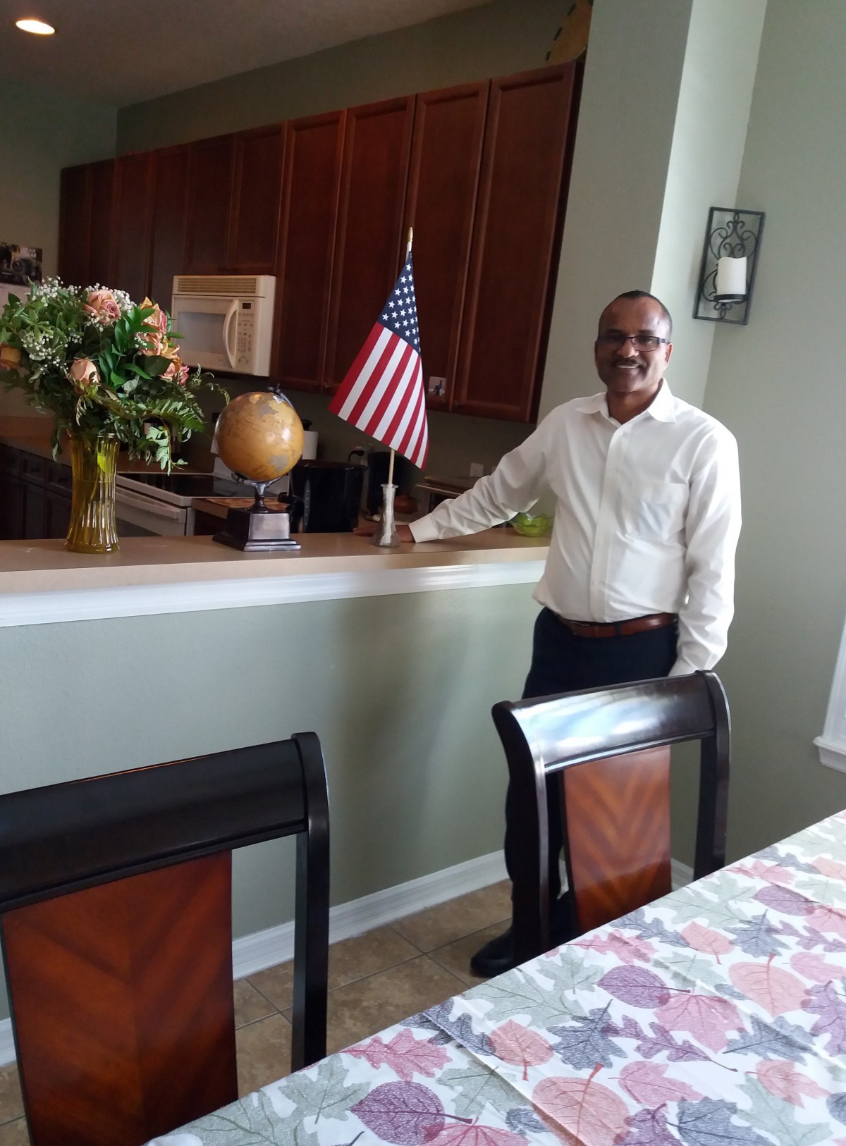 A man standing in a dining area next to an American flag.
