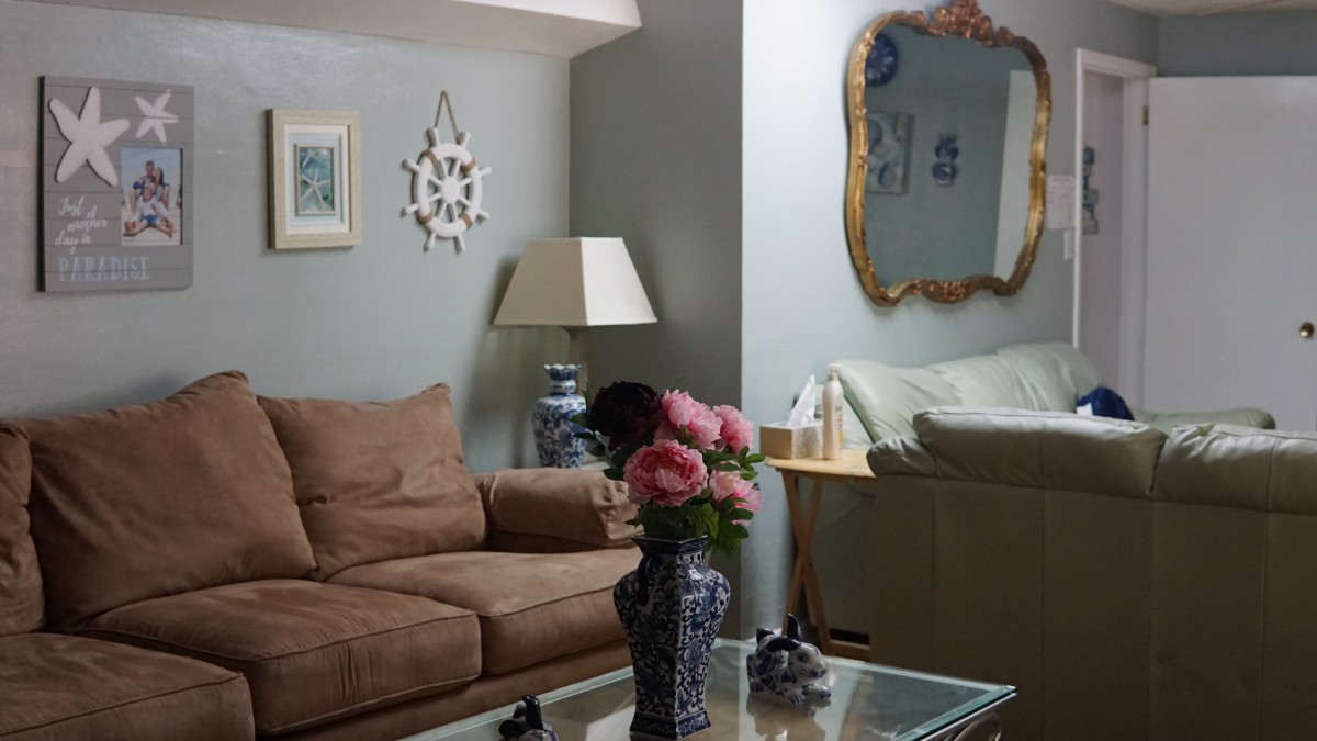 A cozy living room with a sofa, decorative mirror, and floral arrangement.