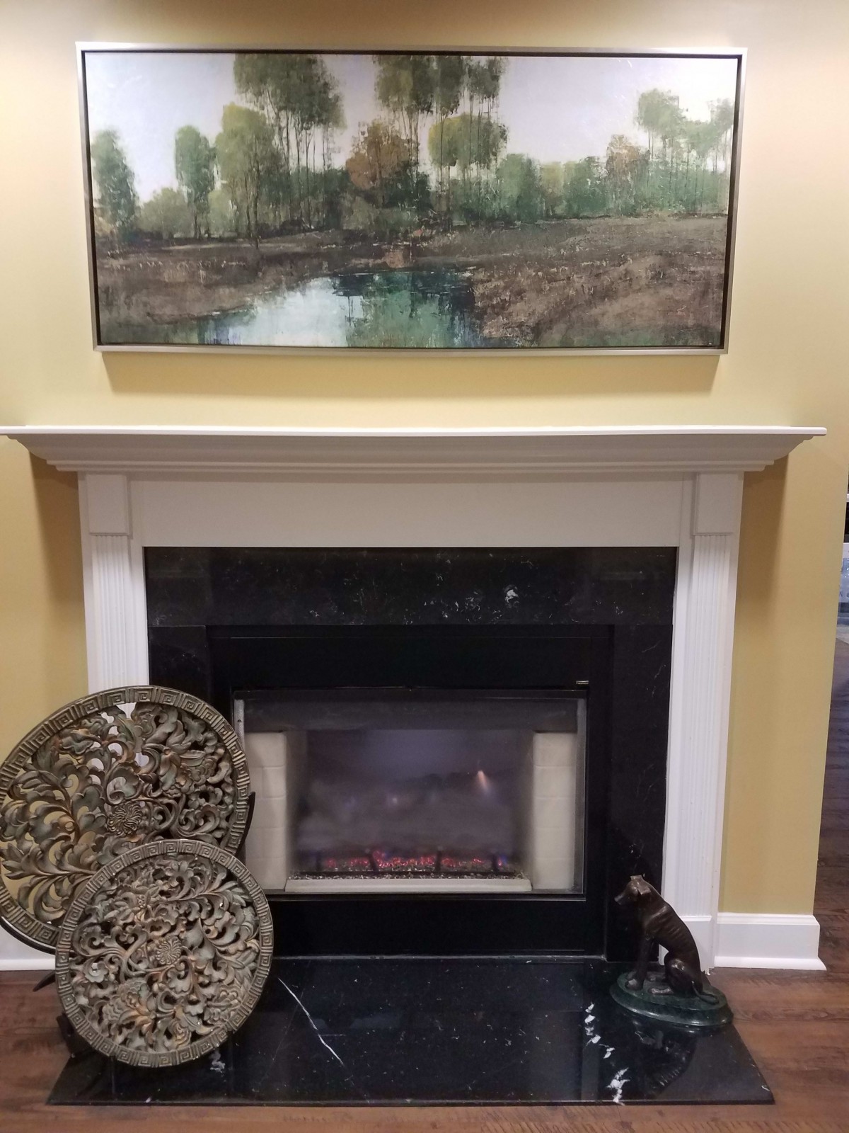 A cozy living room scene featuring a fireplace, elegant decorations, and a landscape painting above the mantel.