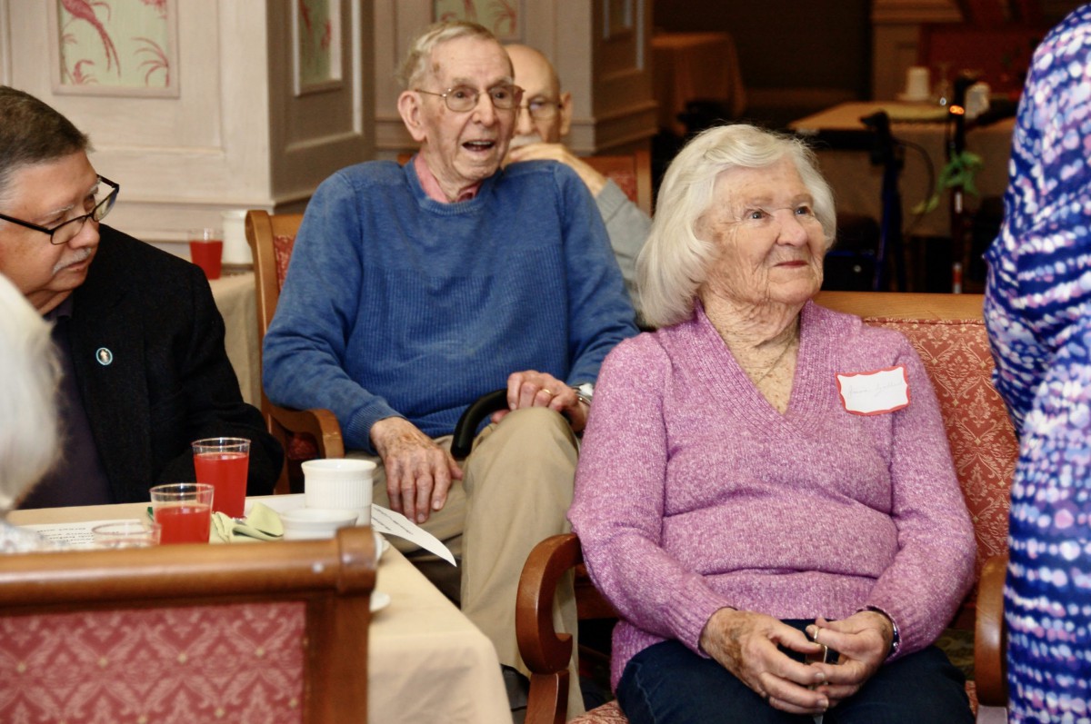 A group of elderly individuals enjoying a gathering indoors.