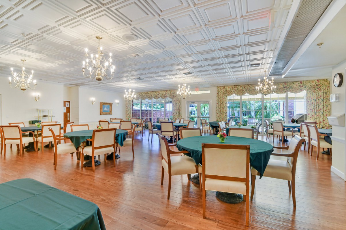 A spacious dining room with elegantly set tables and chandeliers.