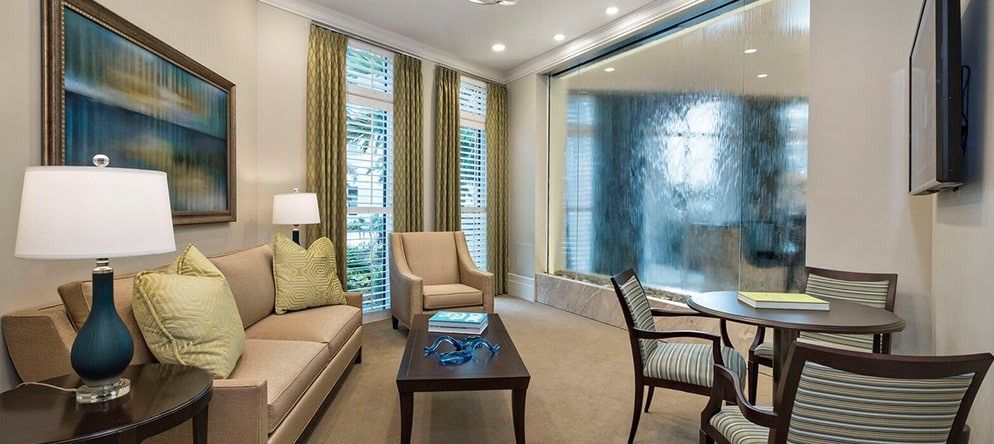 A modern living room with comfortable seating, including a sofa and armchairs, complemented by elegant window treatments.
