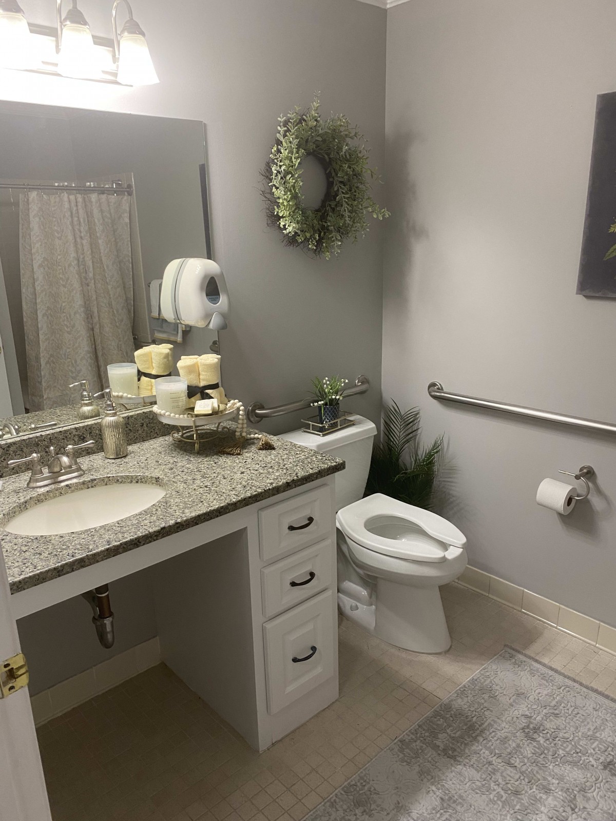 A well-organized bathroom with a granite countertop, decorative wreath, and safety features.