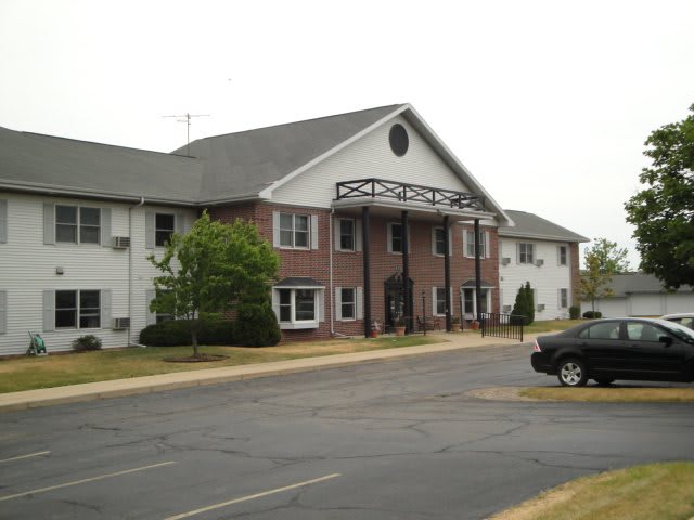 A view of a residential apartment building with a parking lot in front.