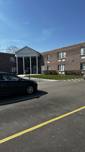 A view of a residential building with a parked car in a well-lit parking lot.