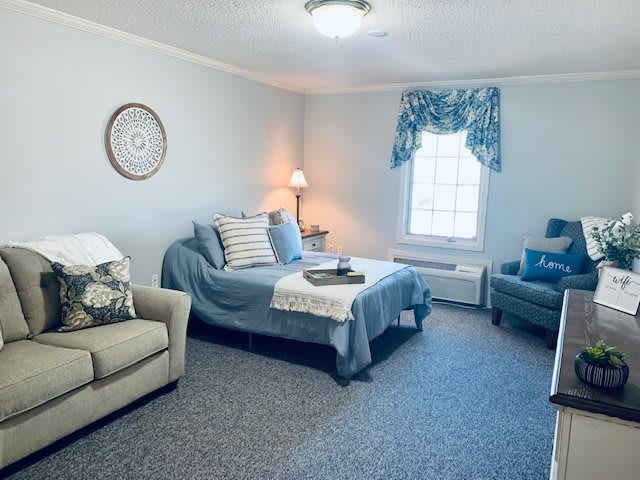 A cozy living room featuring a sofa, bed, and soft lighting.