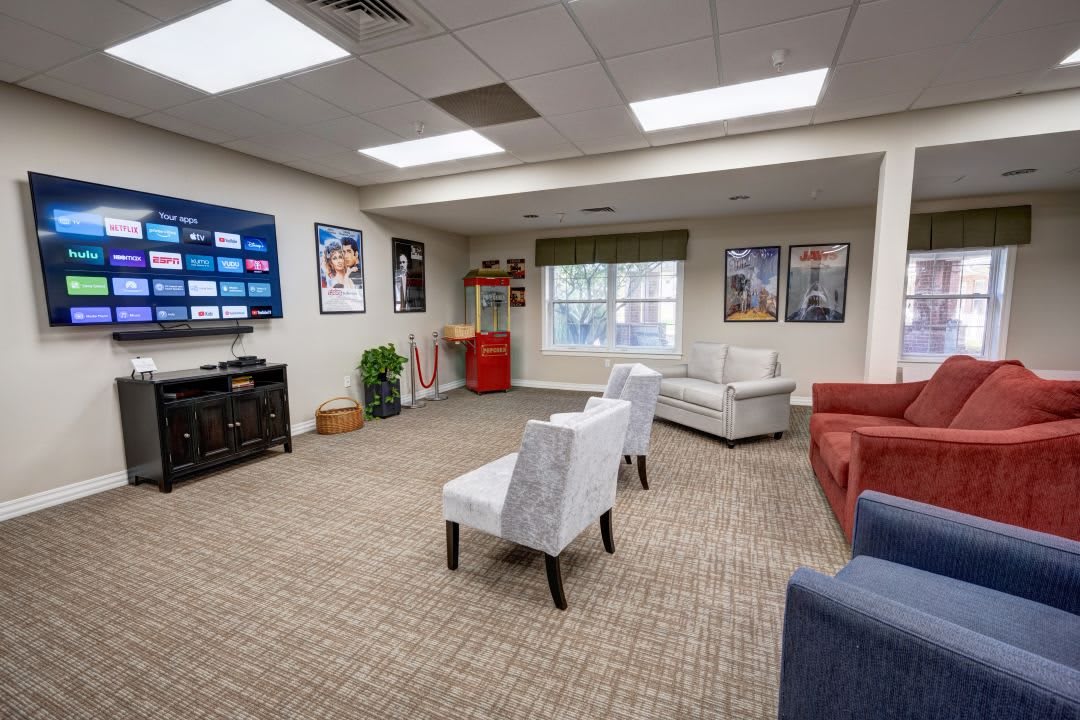 A modern lounge area with comfortable seating, a large TV, and decorative posters on the walls.