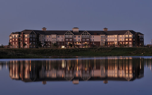A serene lakeside hotel beautifully illuminated at dusk, reflecting on the water.