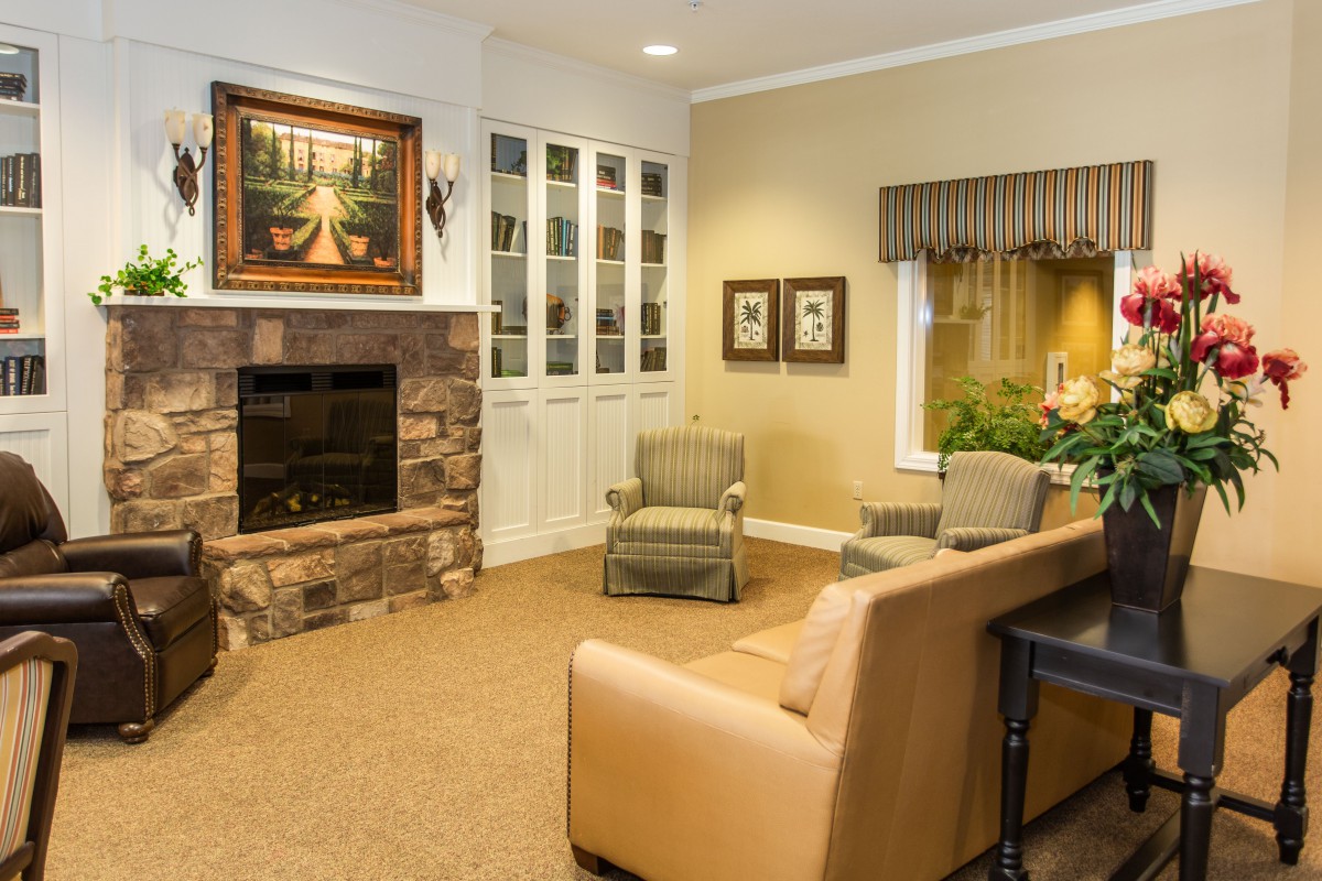 A cozy living room with a stone fireplace, armchairs, and a sofa under warm lighting.