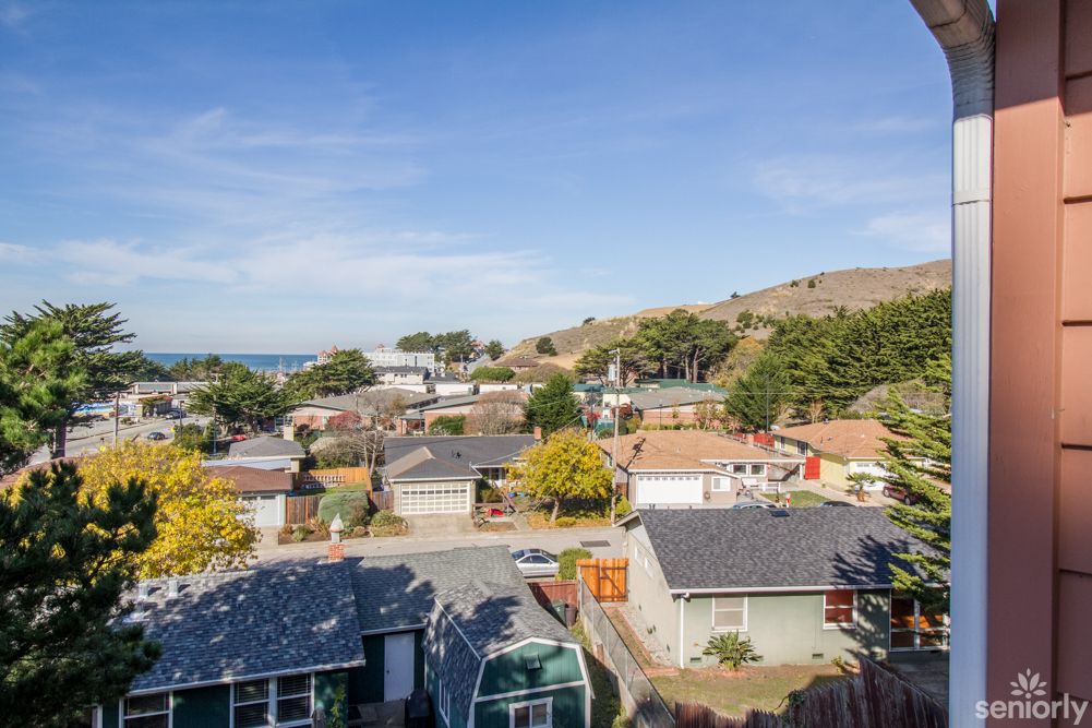 A suburban neighborhood with houses and rolling hills in the background.