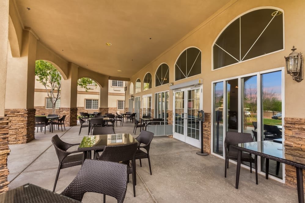 An outdoor patio with tables and chairs, featuring arched windows and glass doors.