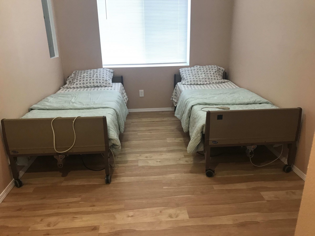 A minimalist bedroom with two twin beds and a window.