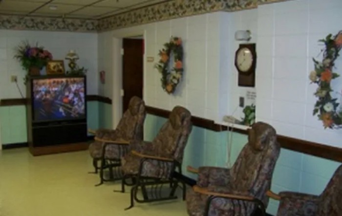 A cozy waiting room with patterned chairs, a wall clock, and a vending machine.