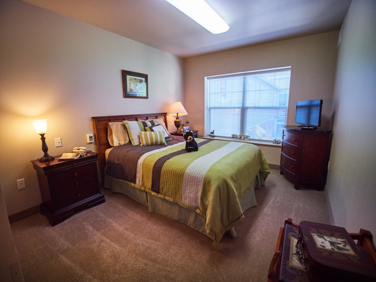 A cozy, well-decorated bedroom with a large window and a neatly made bed.