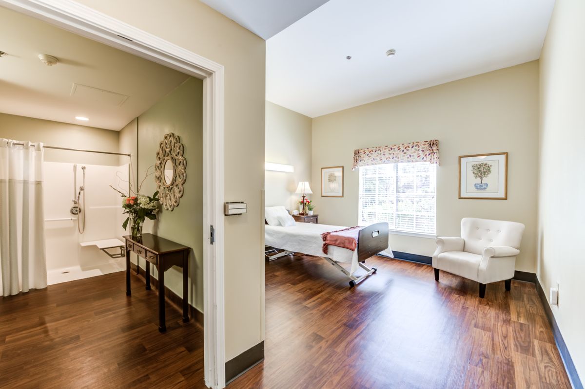 A well-lit hospital patient room with a bed, comfortable chair, and elegant decor.