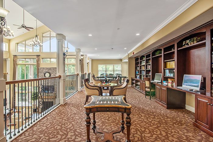 A spacious and elegant library with bookshelves, tables, and a carpeted floor.